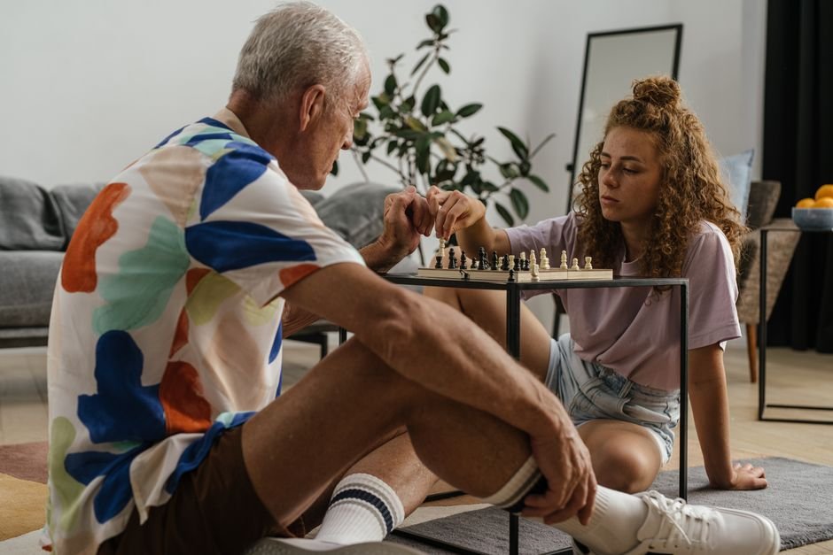 Grandfather and granddaughter doing a behavioral development activity together, playing chess