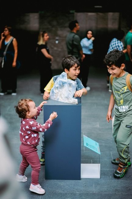 Three children enjoying a fun exhibit in a museum, exploring with excitement