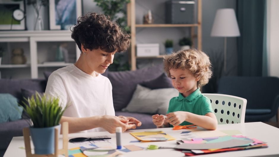 An adult and child creating crafts together at a table