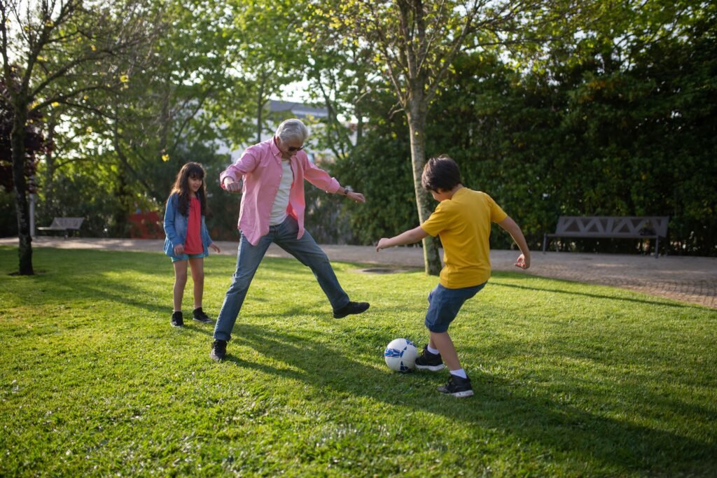 Grandfather playing soccer with his grandchildren in a sunny park
